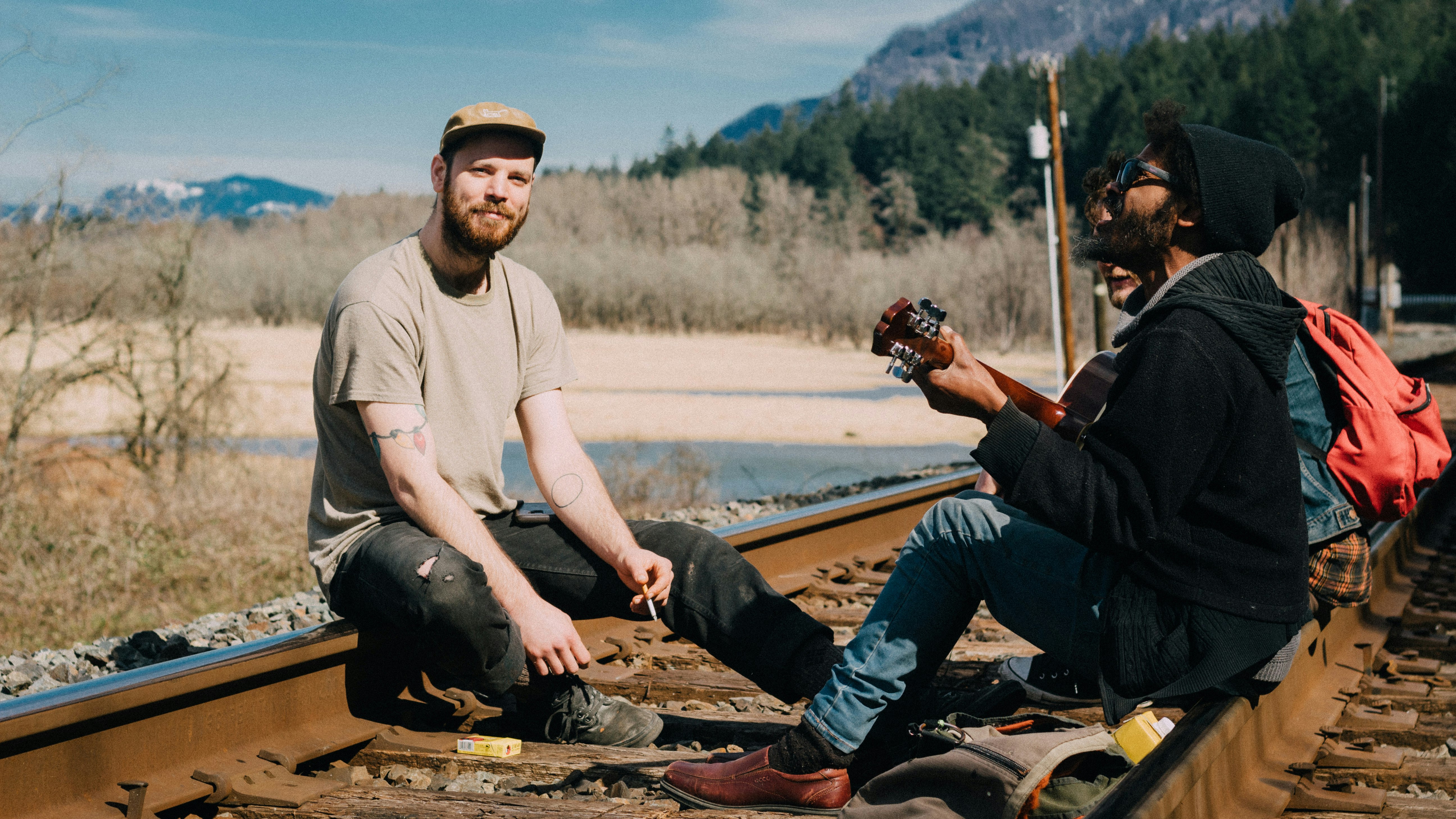 three men sitting on train rails